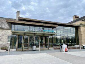 Front glass entrance to the recently renovated visitor center at George Eastman Museum. Sign for Open Face sits out front.