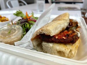Takeout container with Eggplant Parm and a side salad