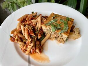 Cauliflower parm on a white plate with whole wheat pasta