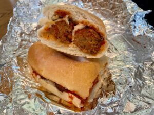 The cross-section of a vegan meatball sub on tin foil