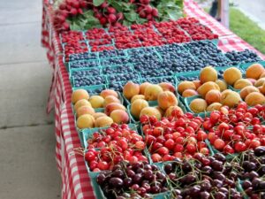Fruit stand at at farmers market showing cherries, blueberries, peaches, and raspberries