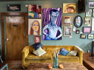 Vintage gold couch set against a blue-green wall. Wall is covered in art.
