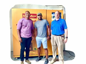 Three men standing in front of a Homechow kiosk smiling
